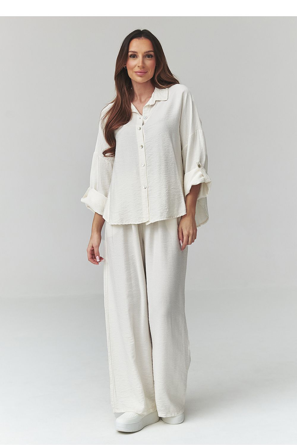 Woman wearing a white outfit on a plain background