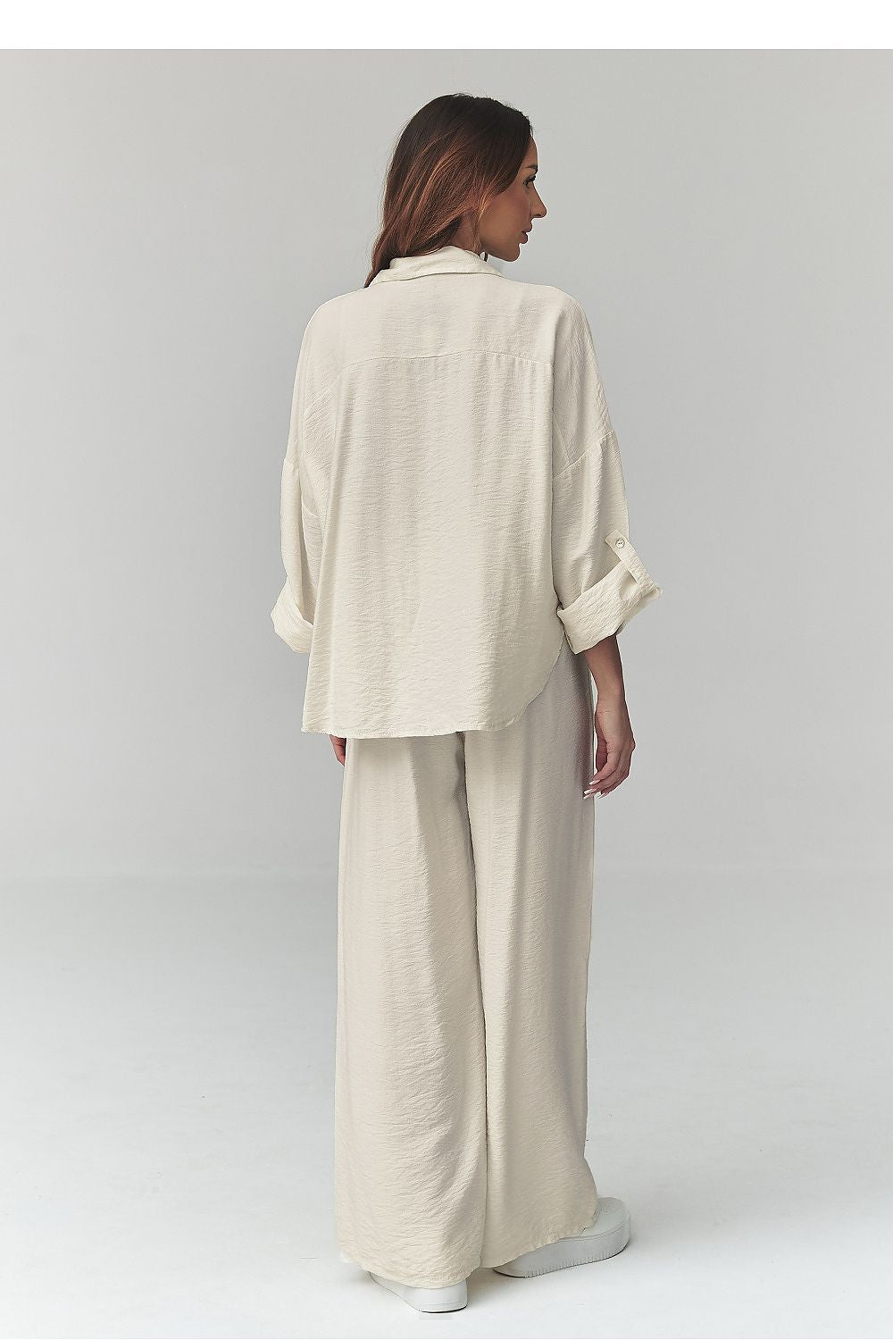Woman wearing a beige outfit on a plain background