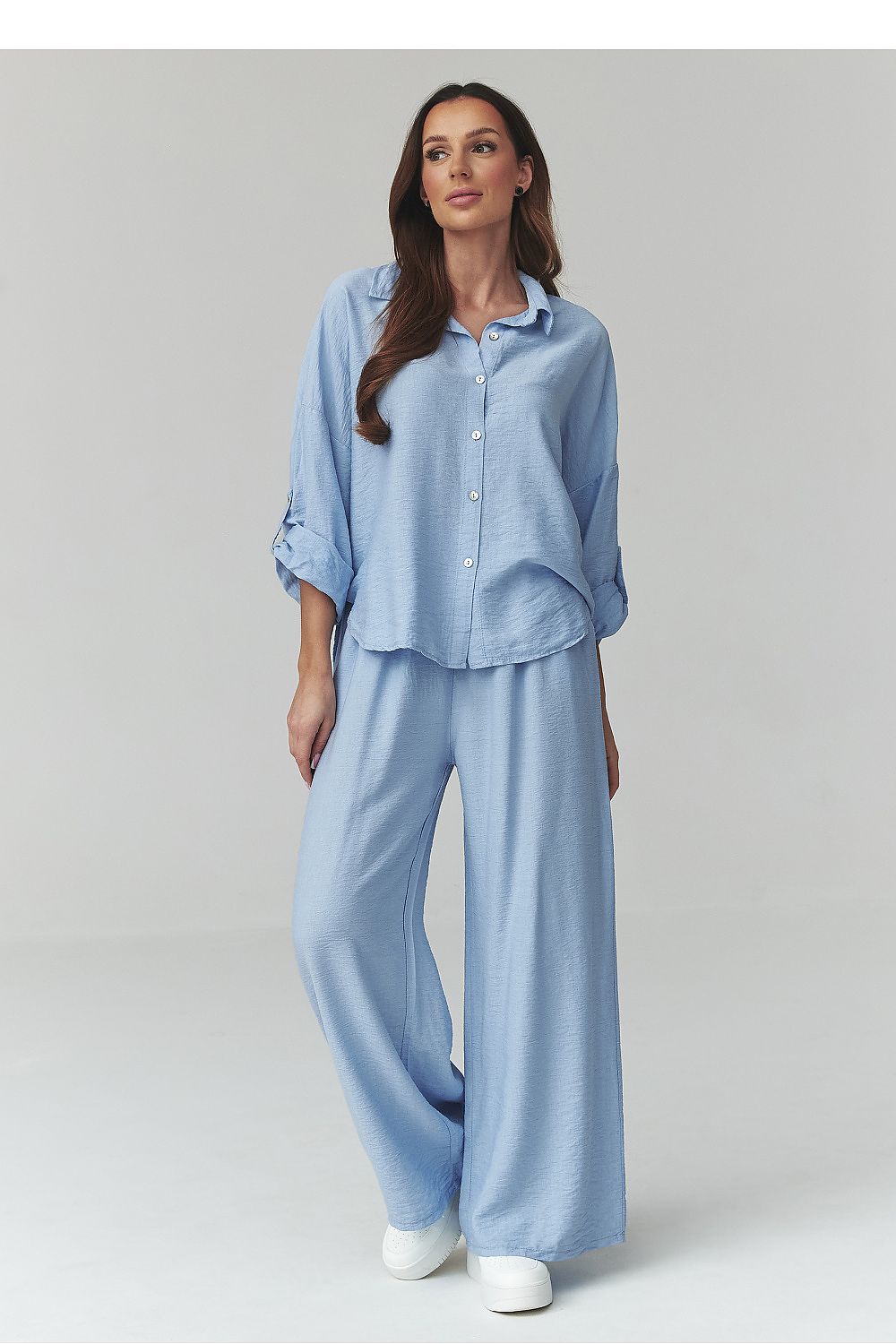 Woman wearing a light blue pajama set on a plain background