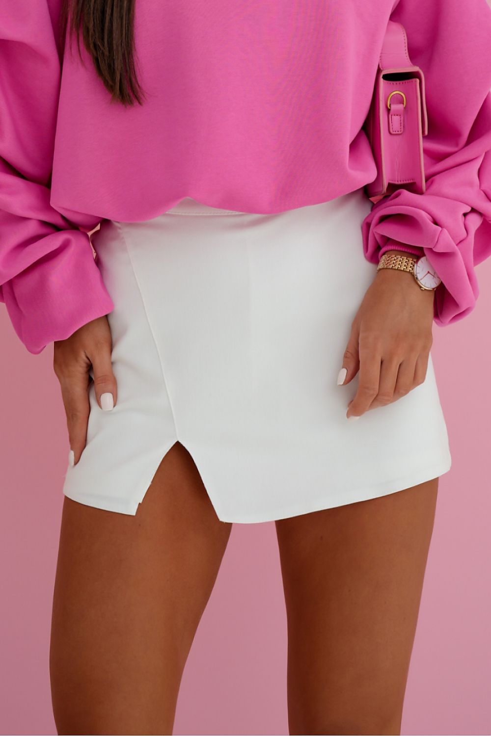 Person wearing a bright pink top and white shorts on a pink background