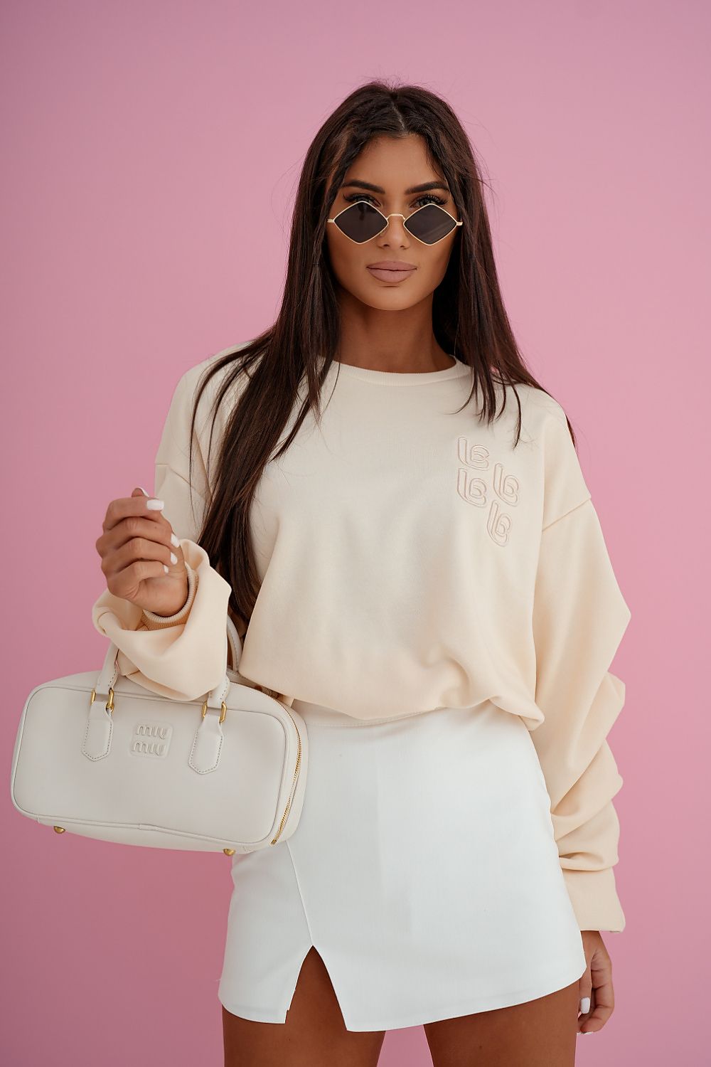Woman holding a white handbag against a pink background