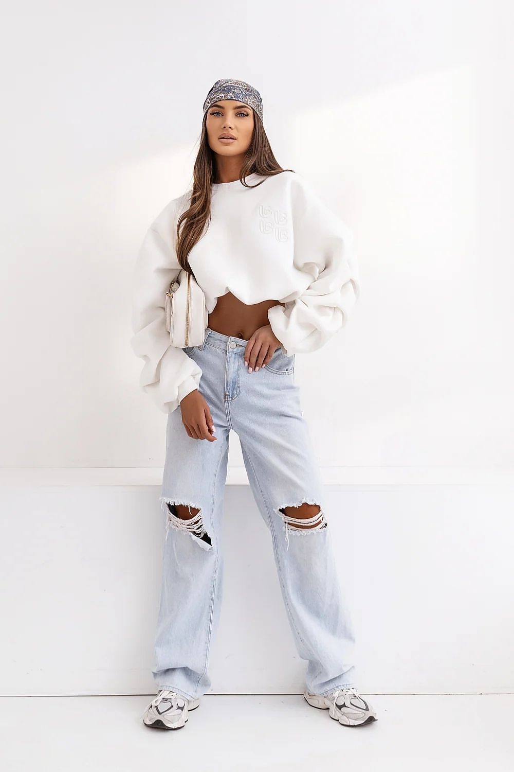 Woman wearing a white outfit with ripped jeans on a white background