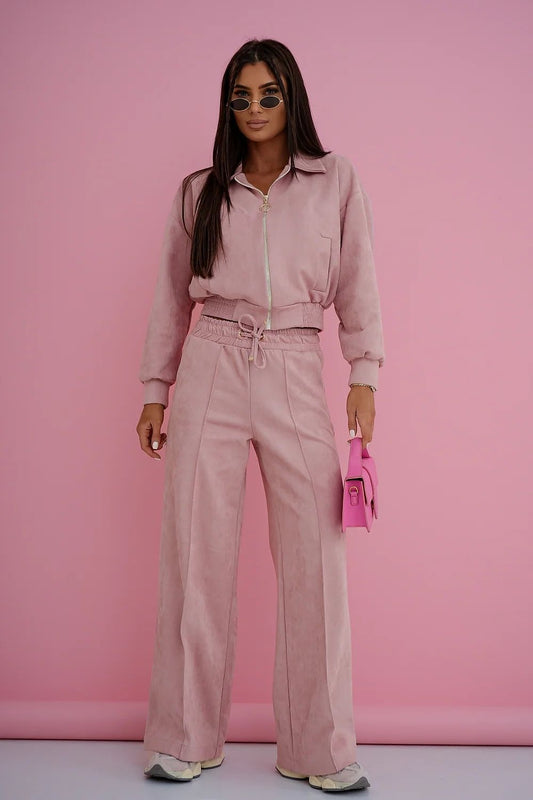 Woman in a pink outfit holding a pink handbag against a pink background