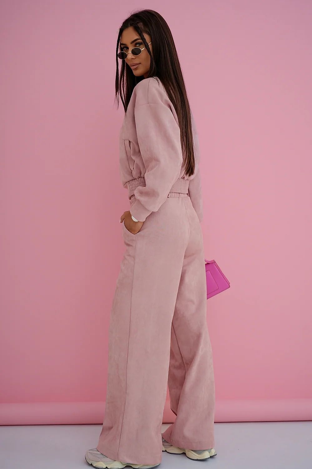 Woman in a pink outfit standing against a pink background