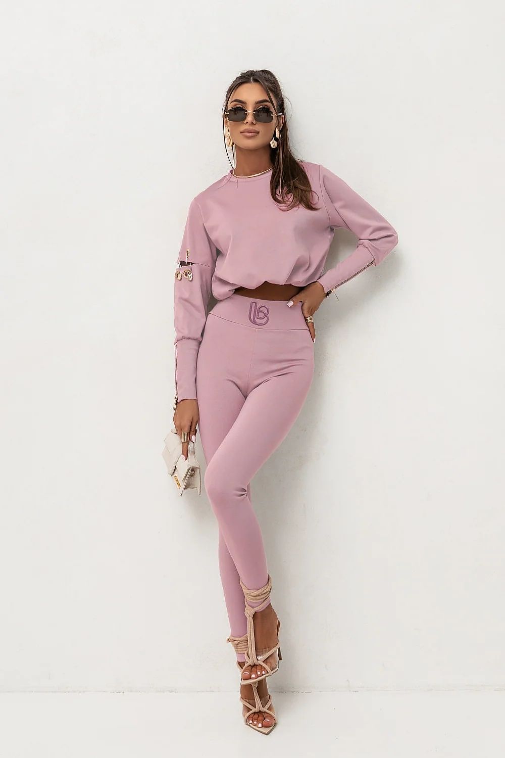 Woman wearing a pink outfit with sunglasses on a white background
