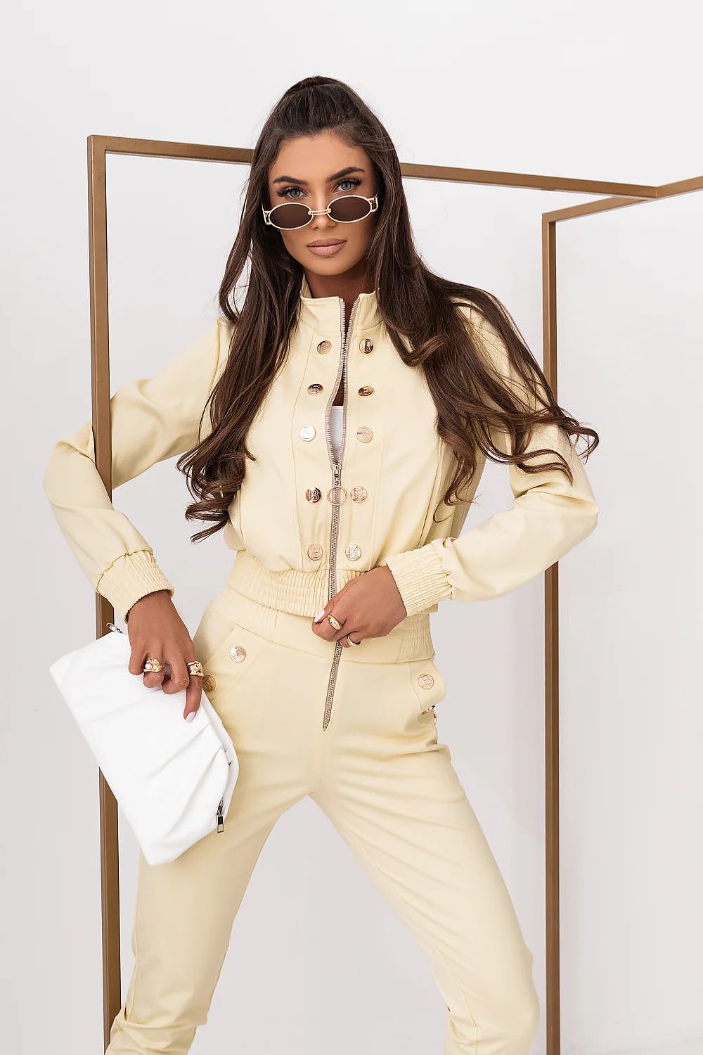 Woman in a beige outfit posing against a white background