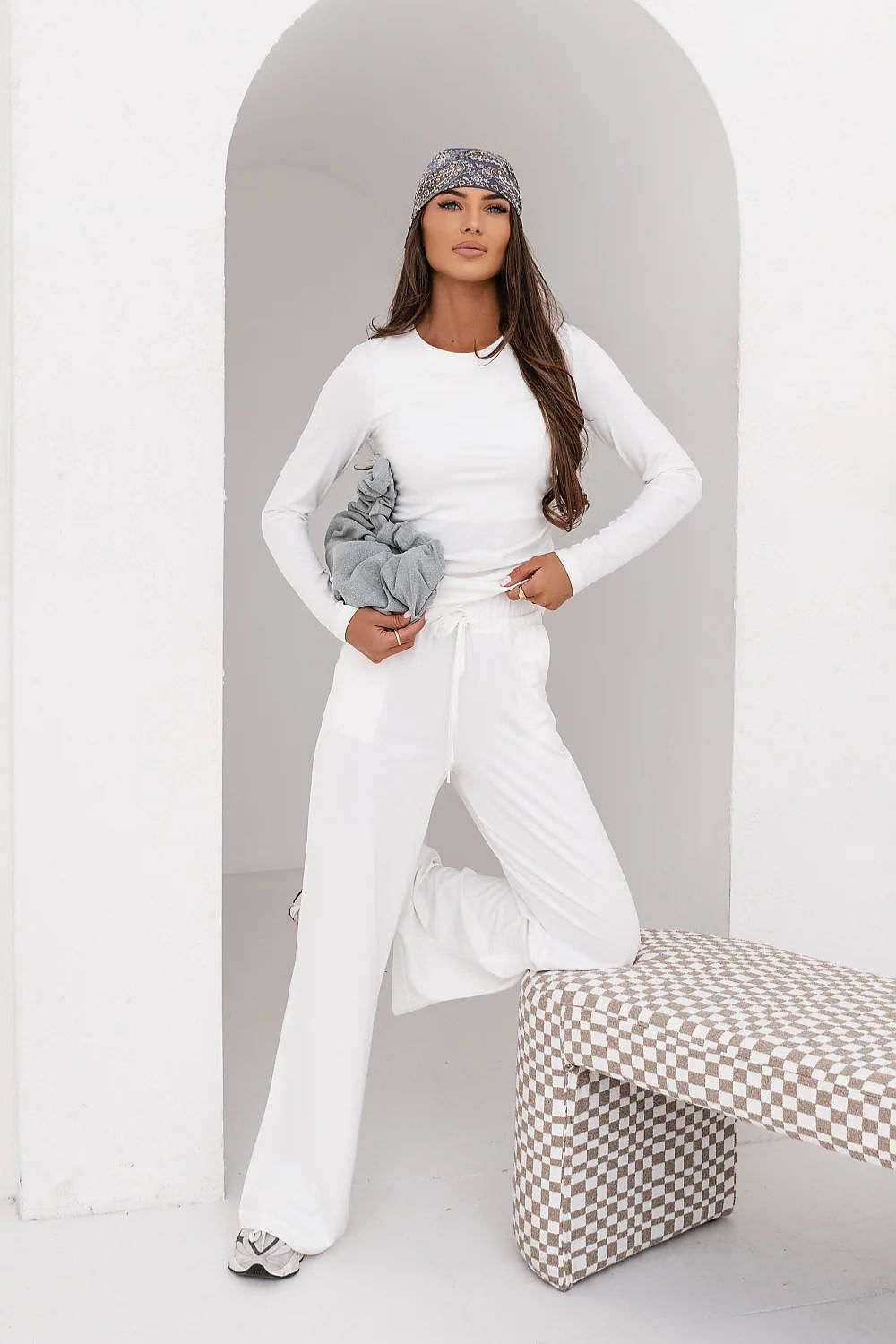 Woman in a white outfit with a checkered pattern in a minimalistic setting