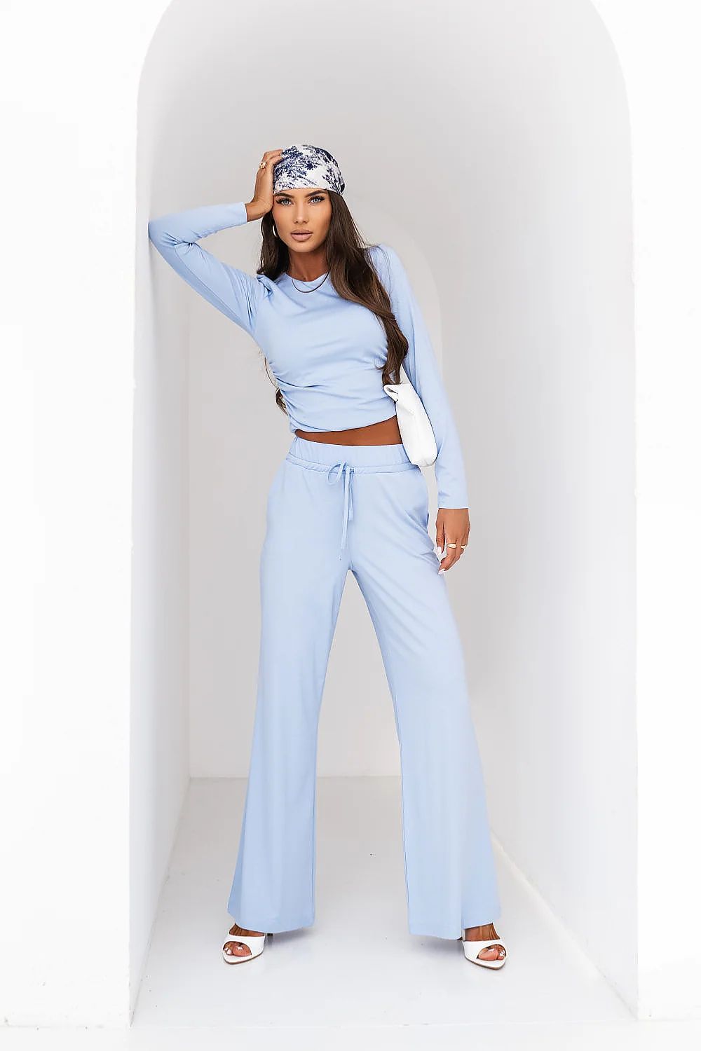 Woman wearing a light blue outfit with a headband against a white background