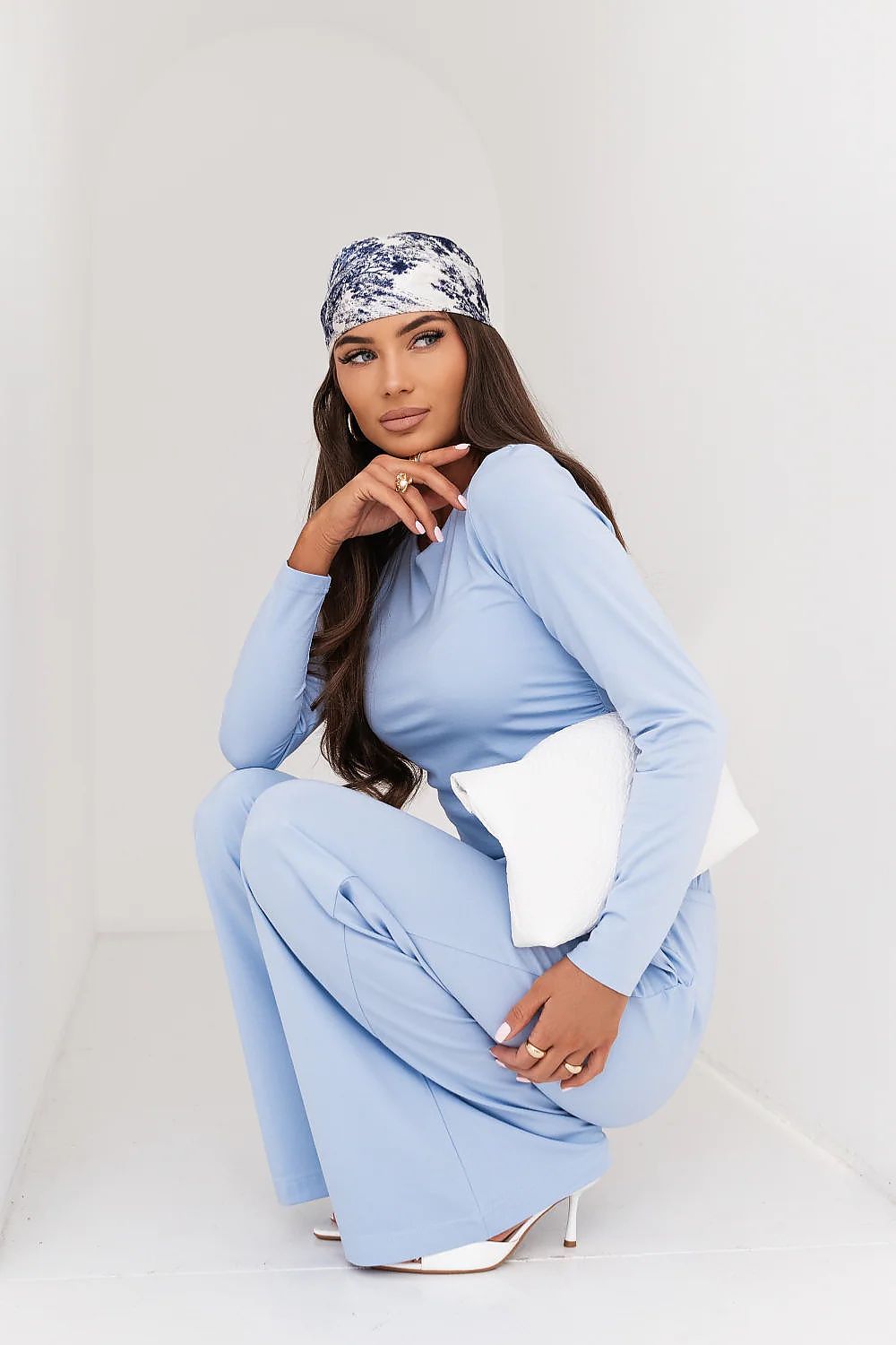 Woman wearing a light blue outfit with a matching headscarf on a white background
