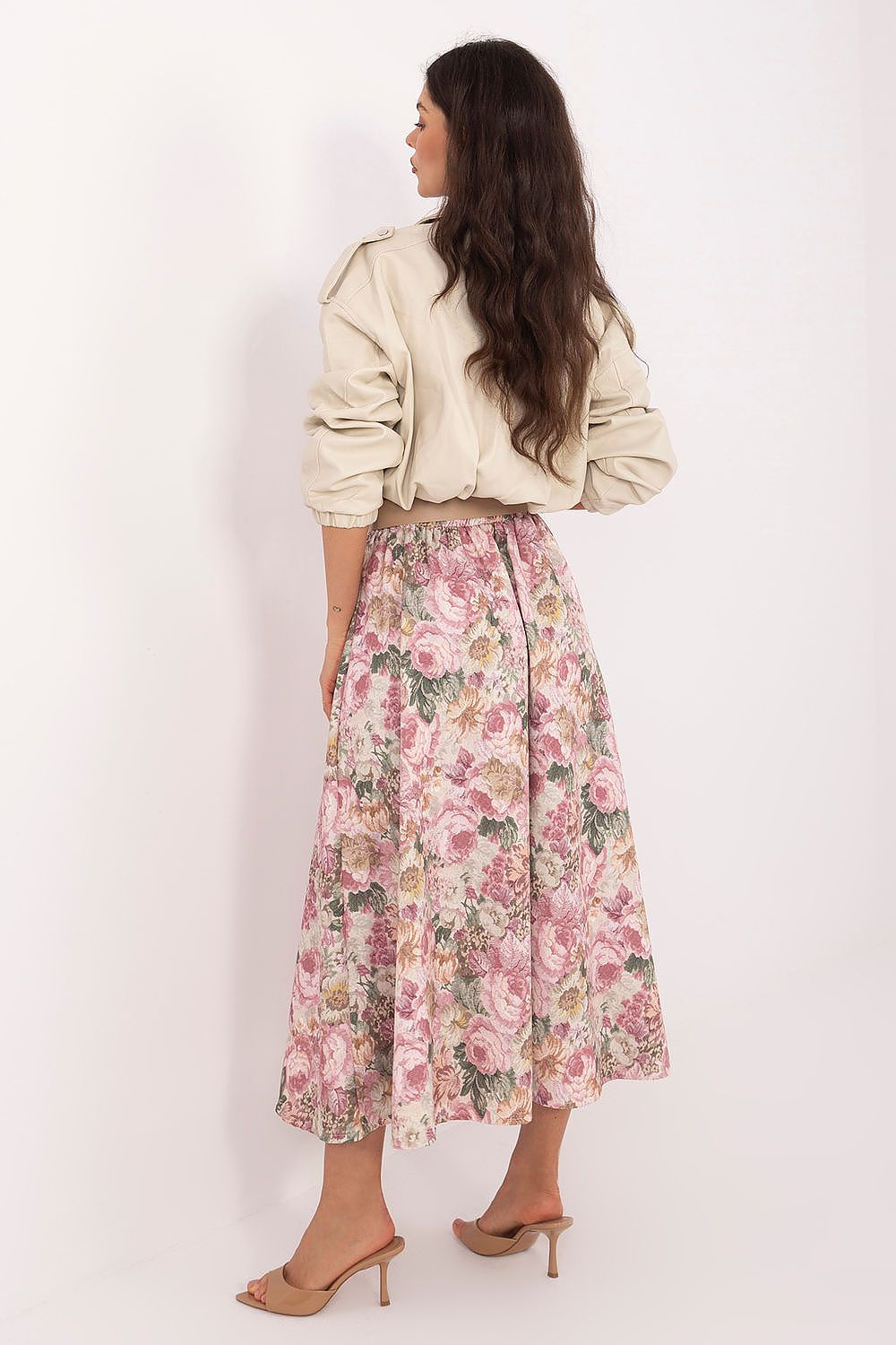 Woman wearing a floral skirt and beige top on a white background
