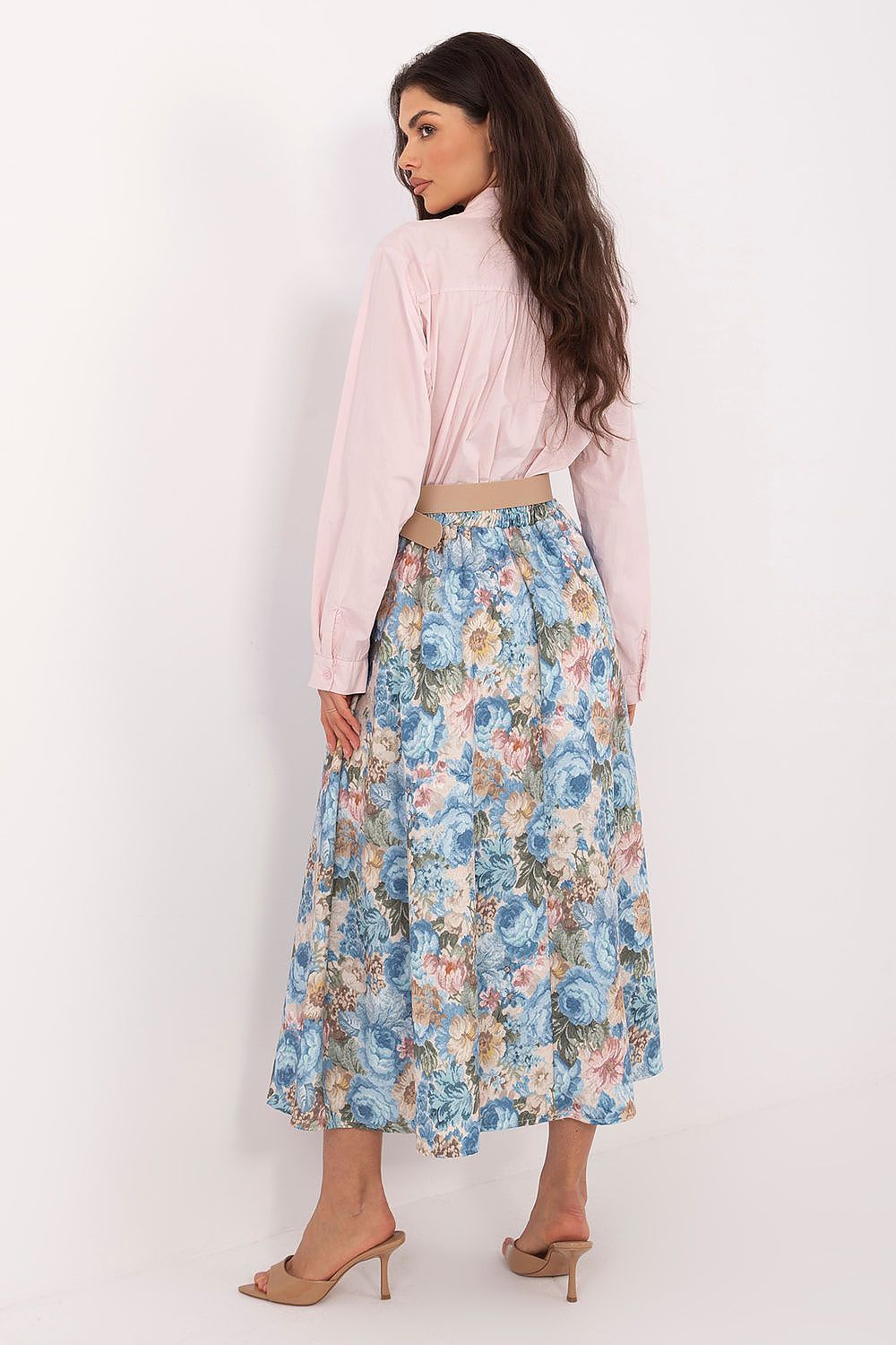 Woman wearing a light pink blouse and floral skirt on a white background