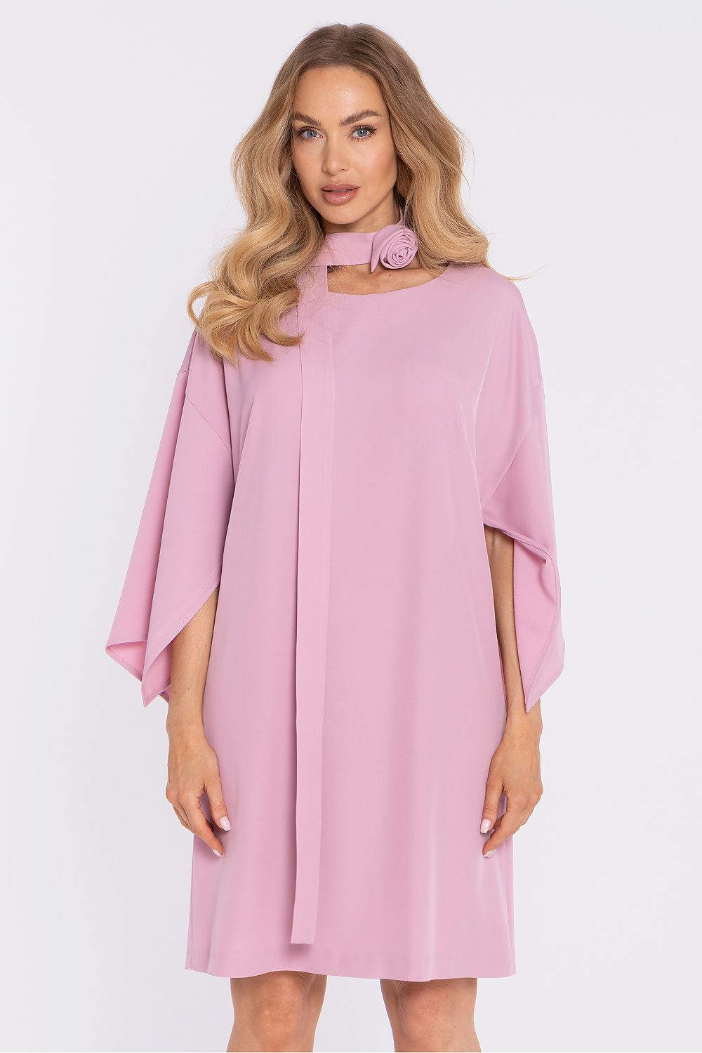 Woman wearing a pink poncho dress against a white background