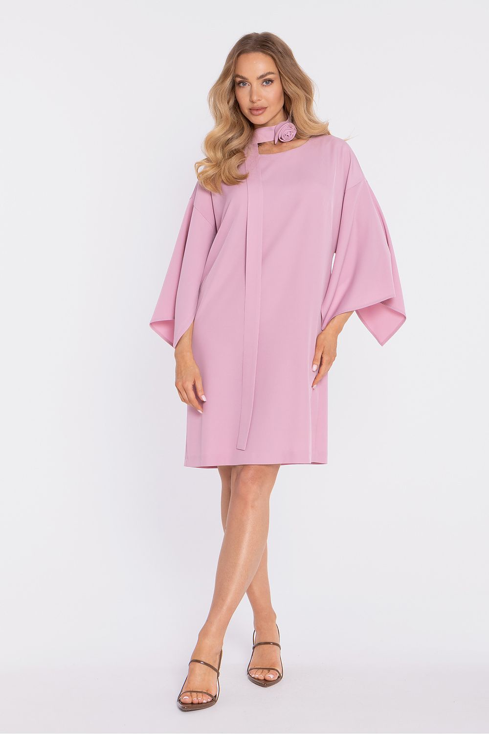 Woman wearing a pink dress with cape sleeves on a white background