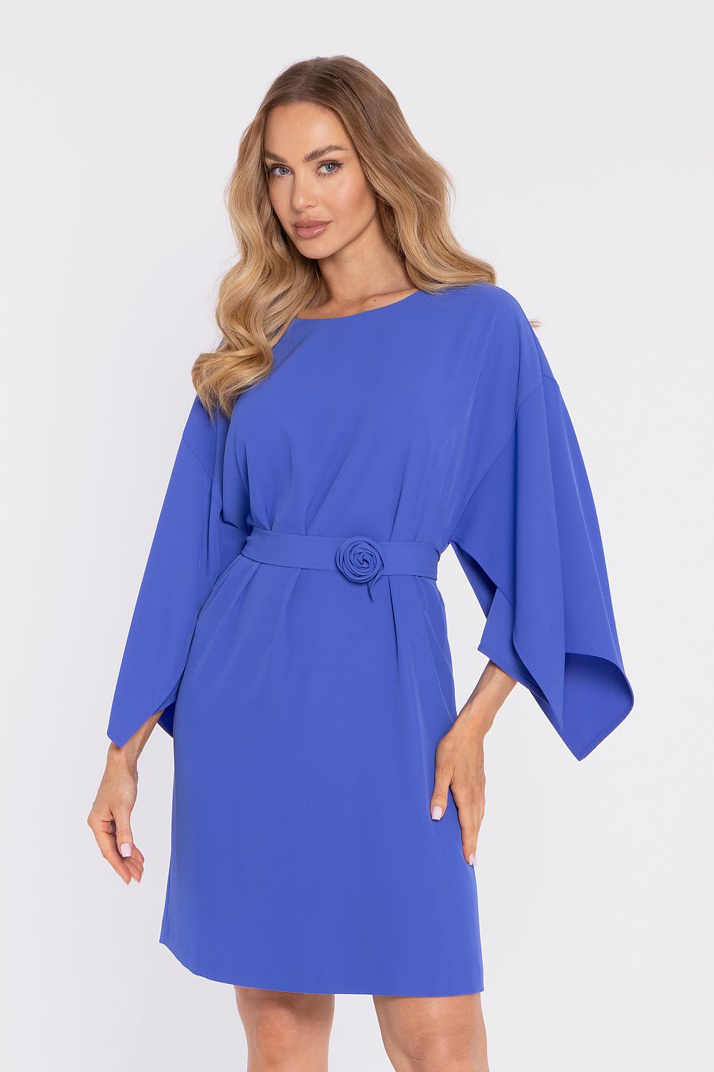 Woman wearing a blue dress with a belt and flower detail on a white background