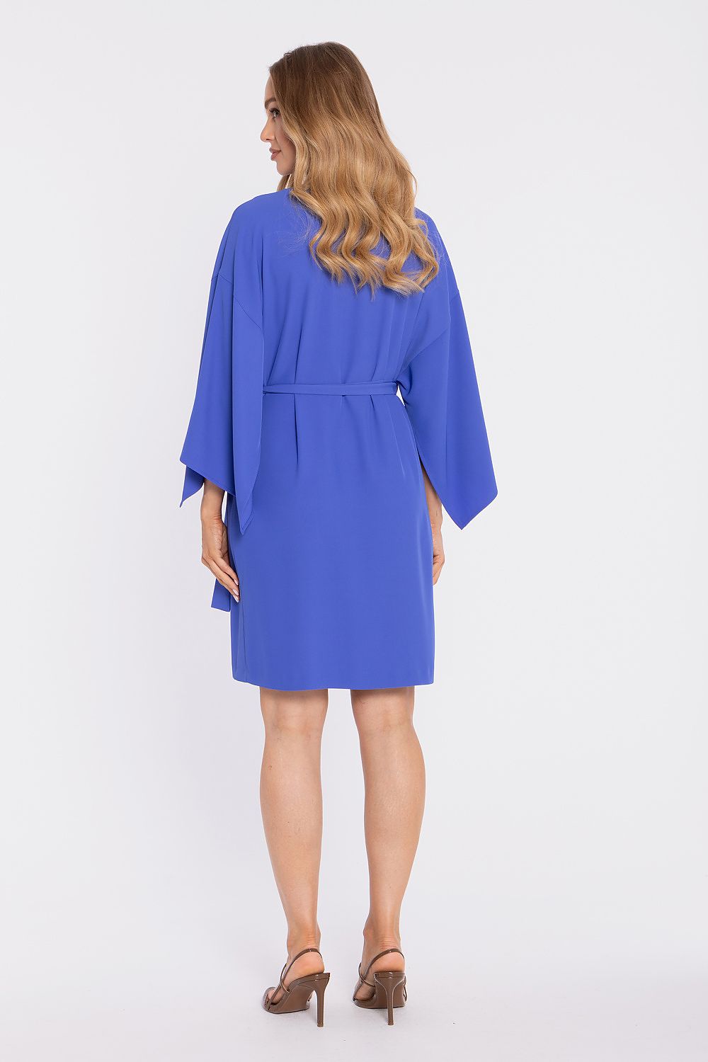 Woman wearing a blue dress with kimono sleeves on a white background