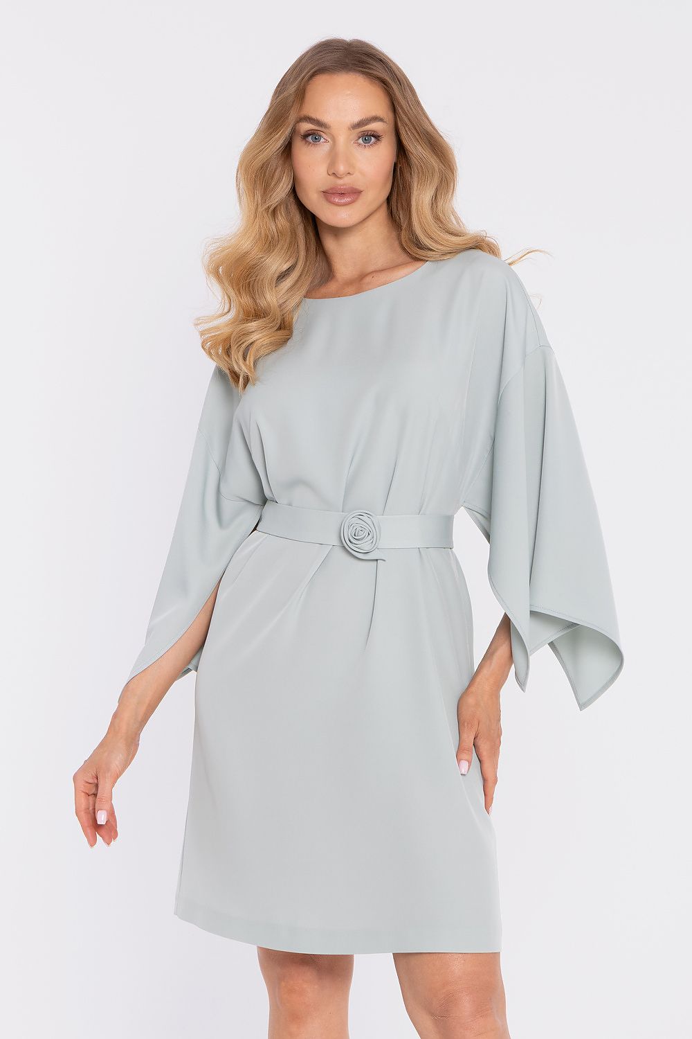 Woman wearing a light gray dress with a belt on a white background