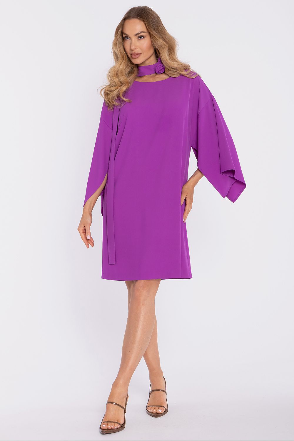 Woman wearing a purple dress with wide sleeves on a white background