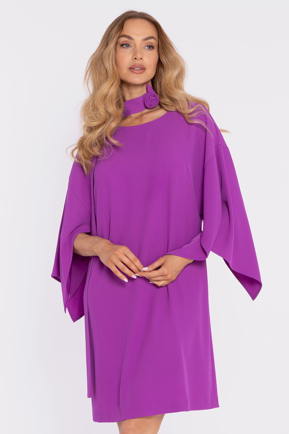 Woman wearing a purple dress with cape sleeves on a white background