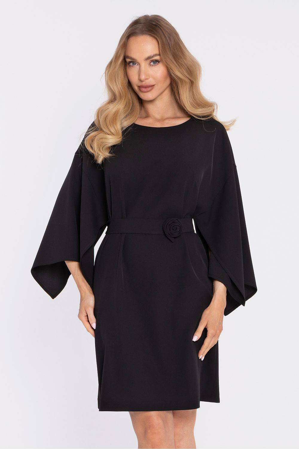 Woman wearing a black dress with cape sleeves on a white background