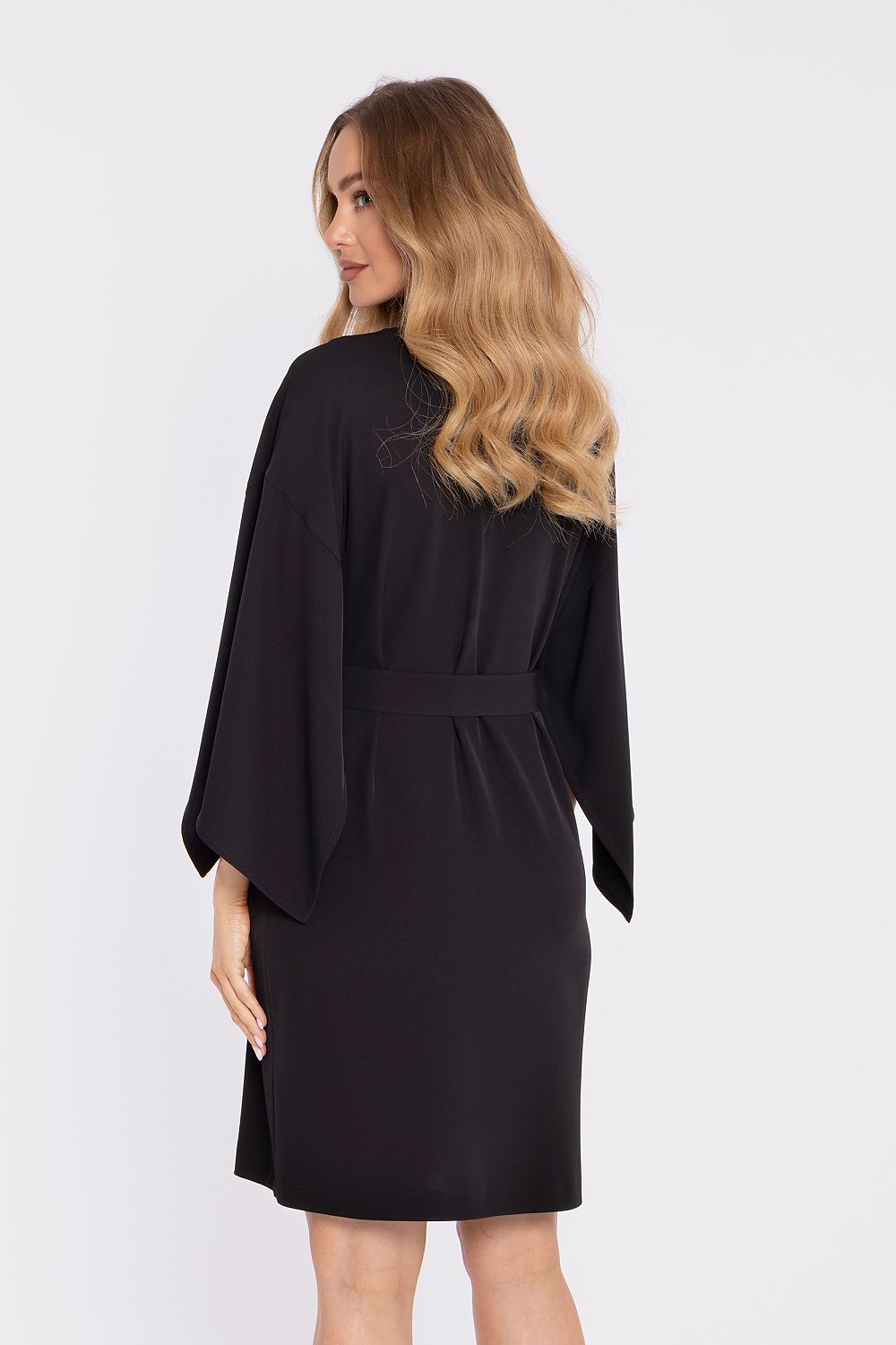 Woman wearing a black dress with a belt on a white background