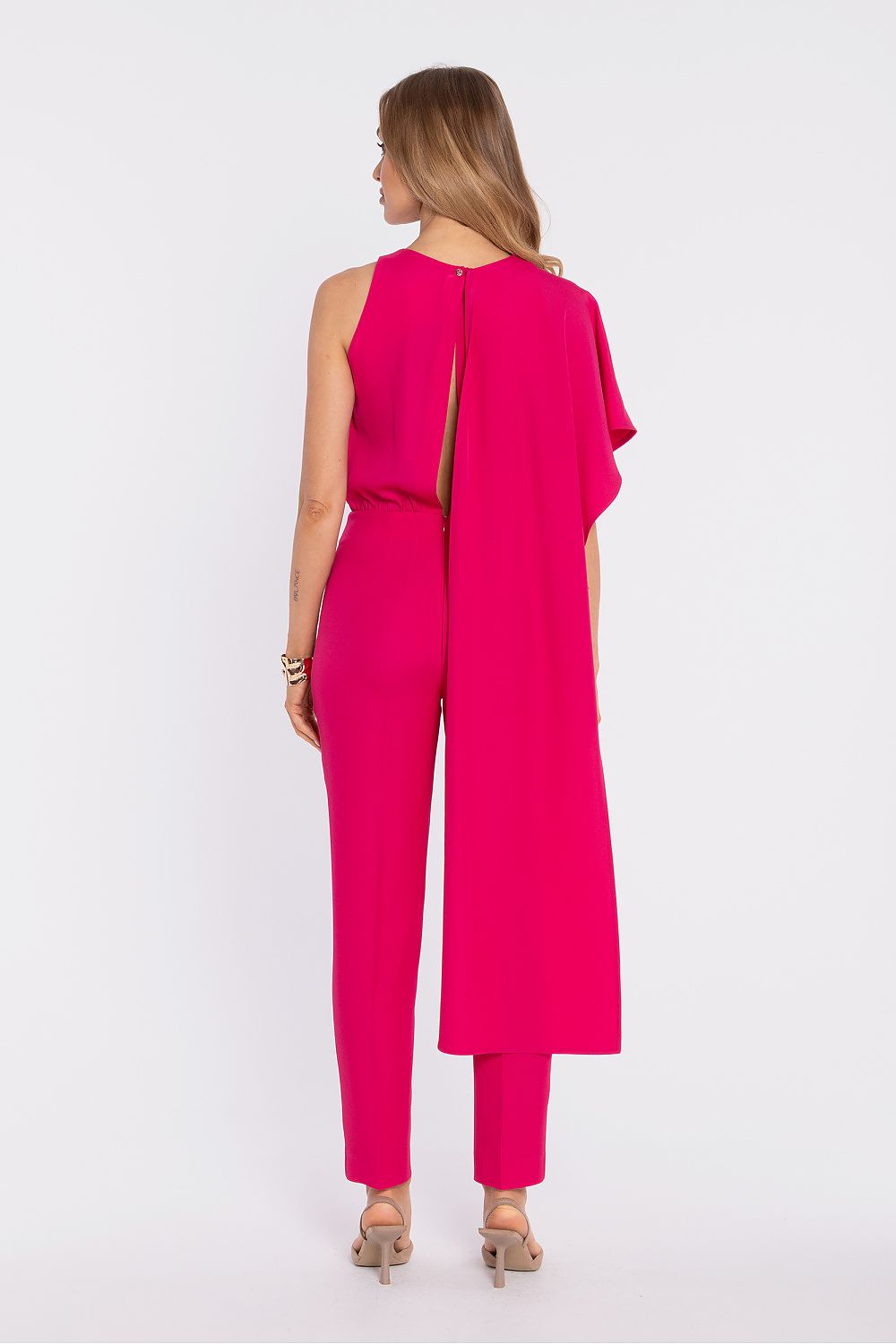 Woman wearing a bright pink jumpsuit on a white background