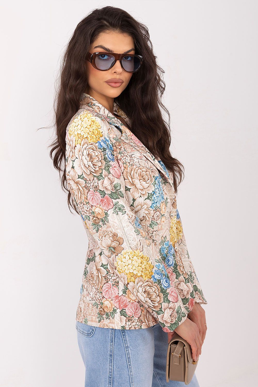 Woman wearing a floral blazer and sunglasses on a white background