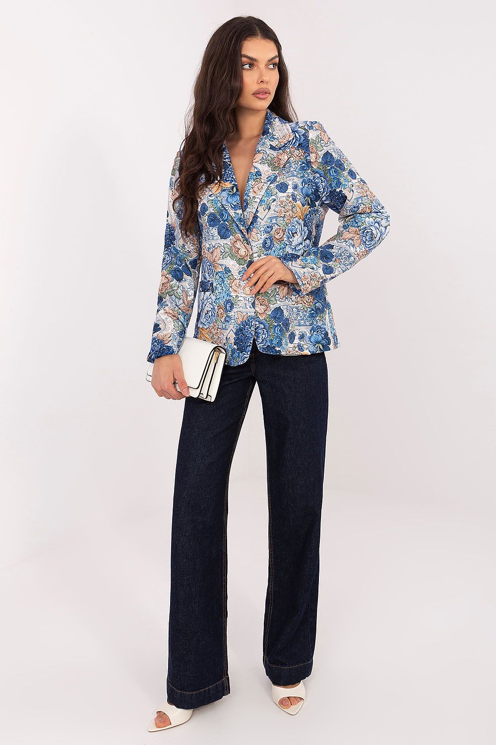Woman wearing a floral blouse and dark jeans on a white background