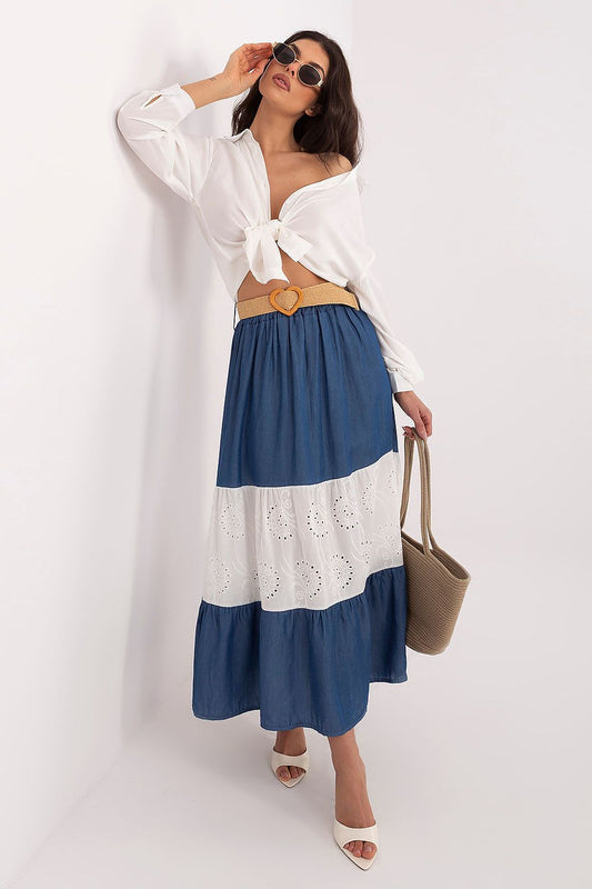 Woman wearing a white top and blue and white striped skirt with sunglasses on a white background