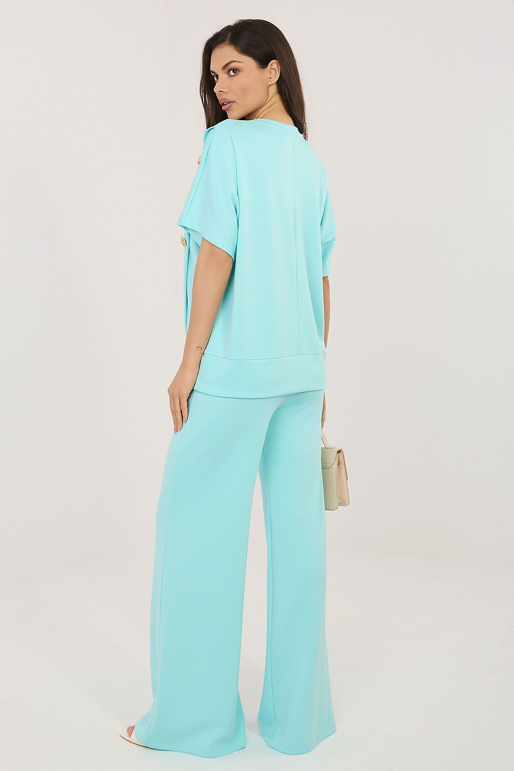 Woman wearing a light blue outfit with wide-leg pants on a white background