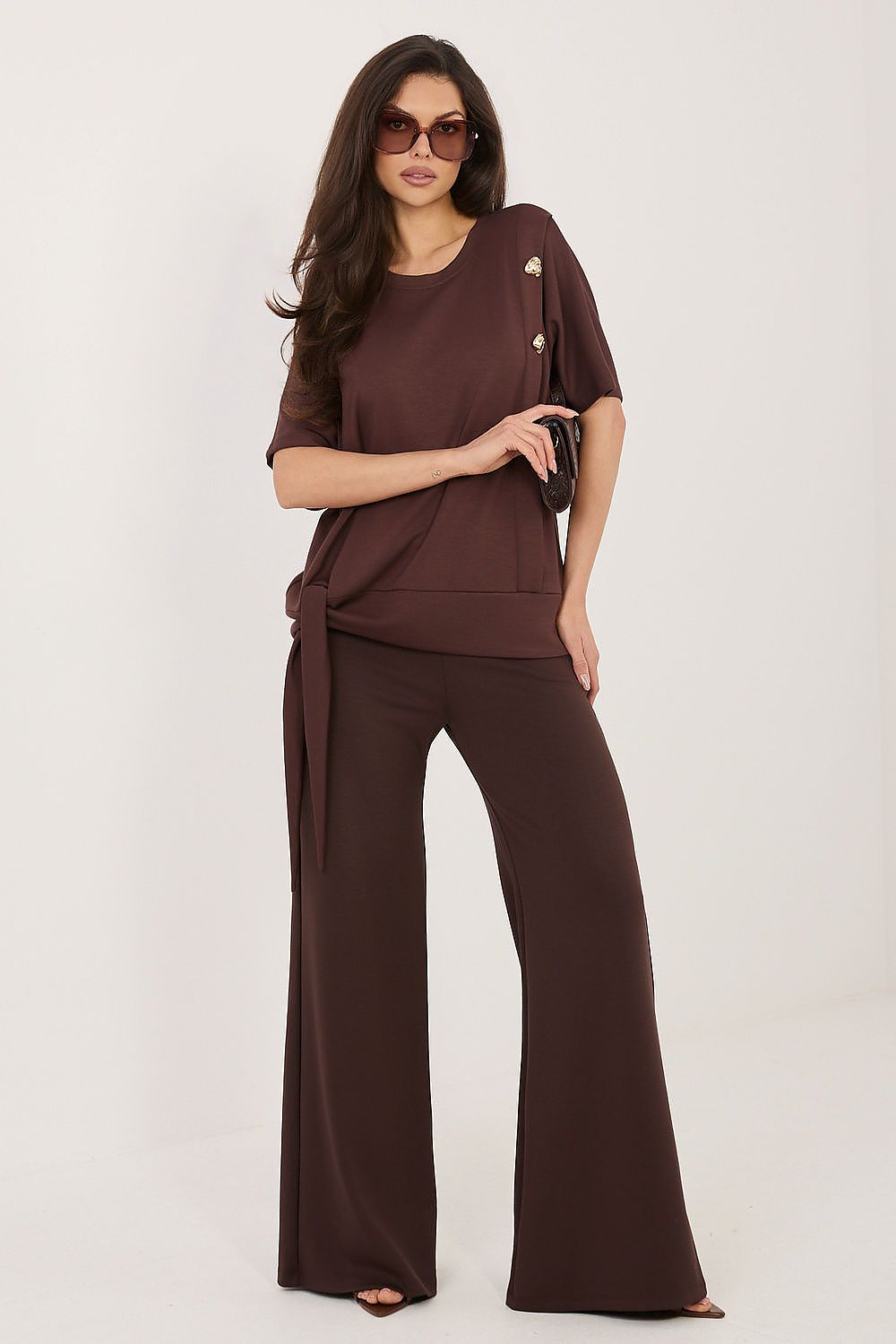 Woman wearing a brown outfit with wide-leg pants on a white background