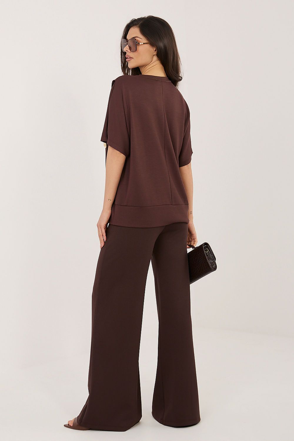 Woman wearing a brown outfit with wide-leg pants on a white background