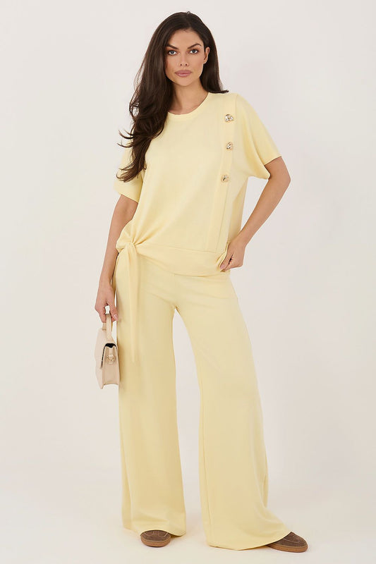 Woman wearing a yellow outfit with wide-leg pants on a white background