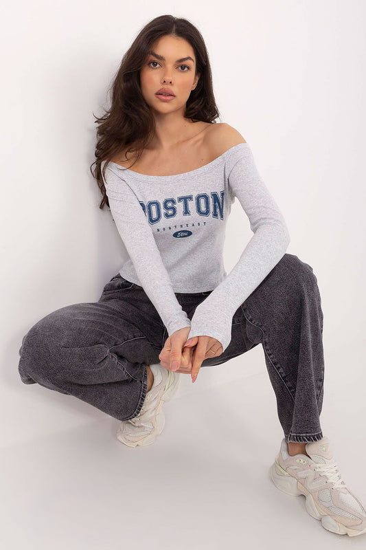 Woman wearing a gray 'Boston' long-sleeve top and dark jeans on a white background
