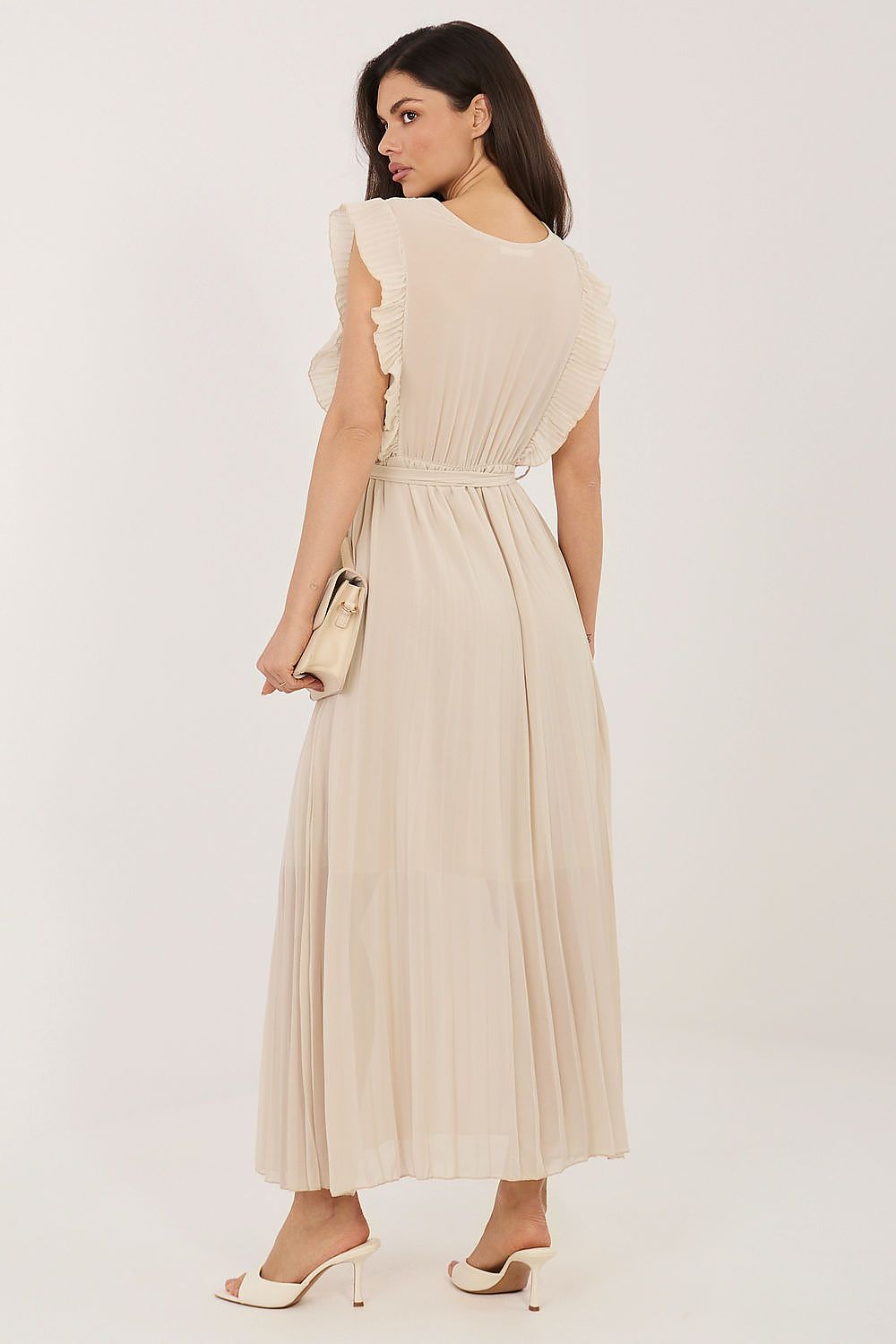 Woman wearing a beige dress with ruffled sleeves on a white background