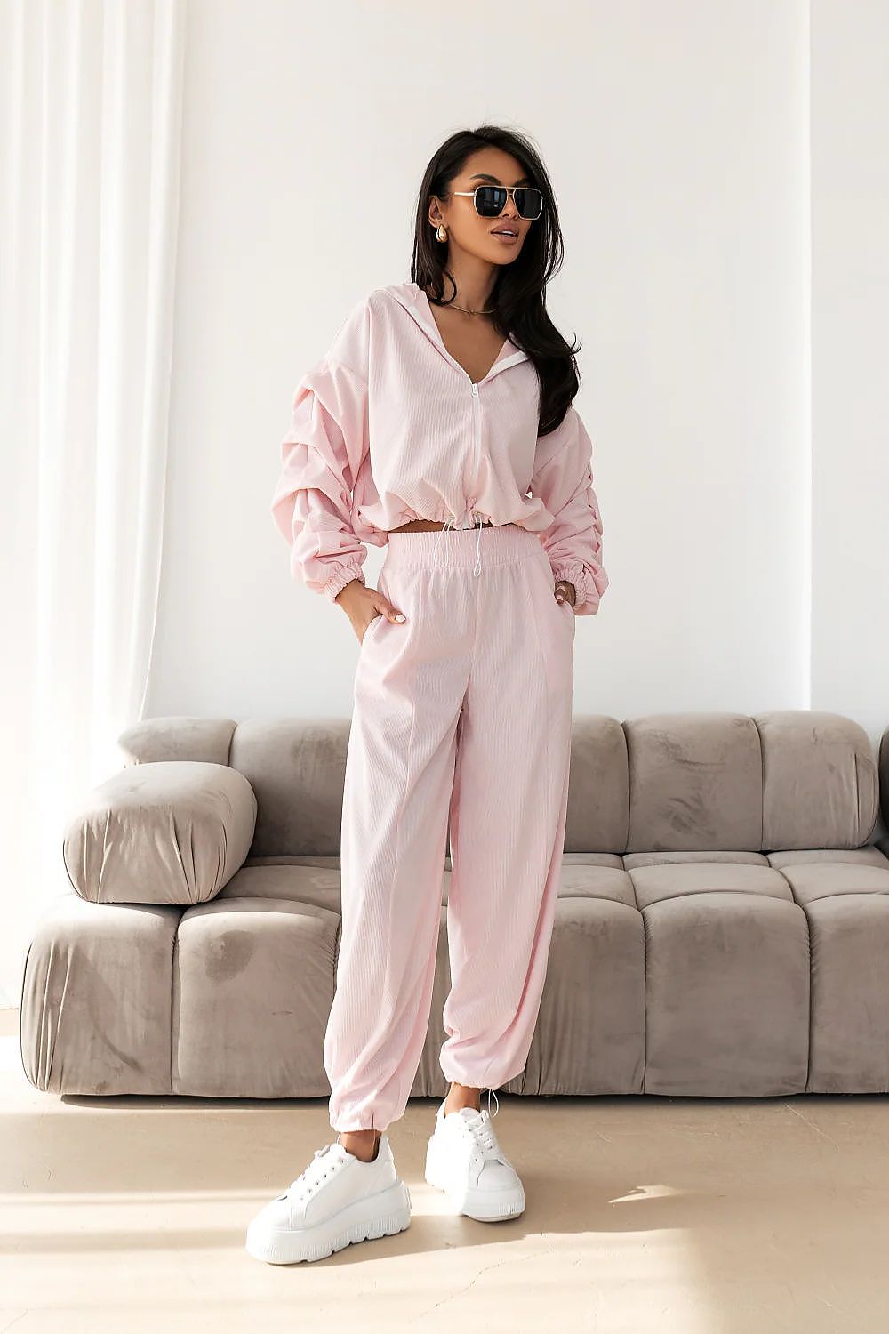 Woman wearing a pink tracksuit in a living room setting