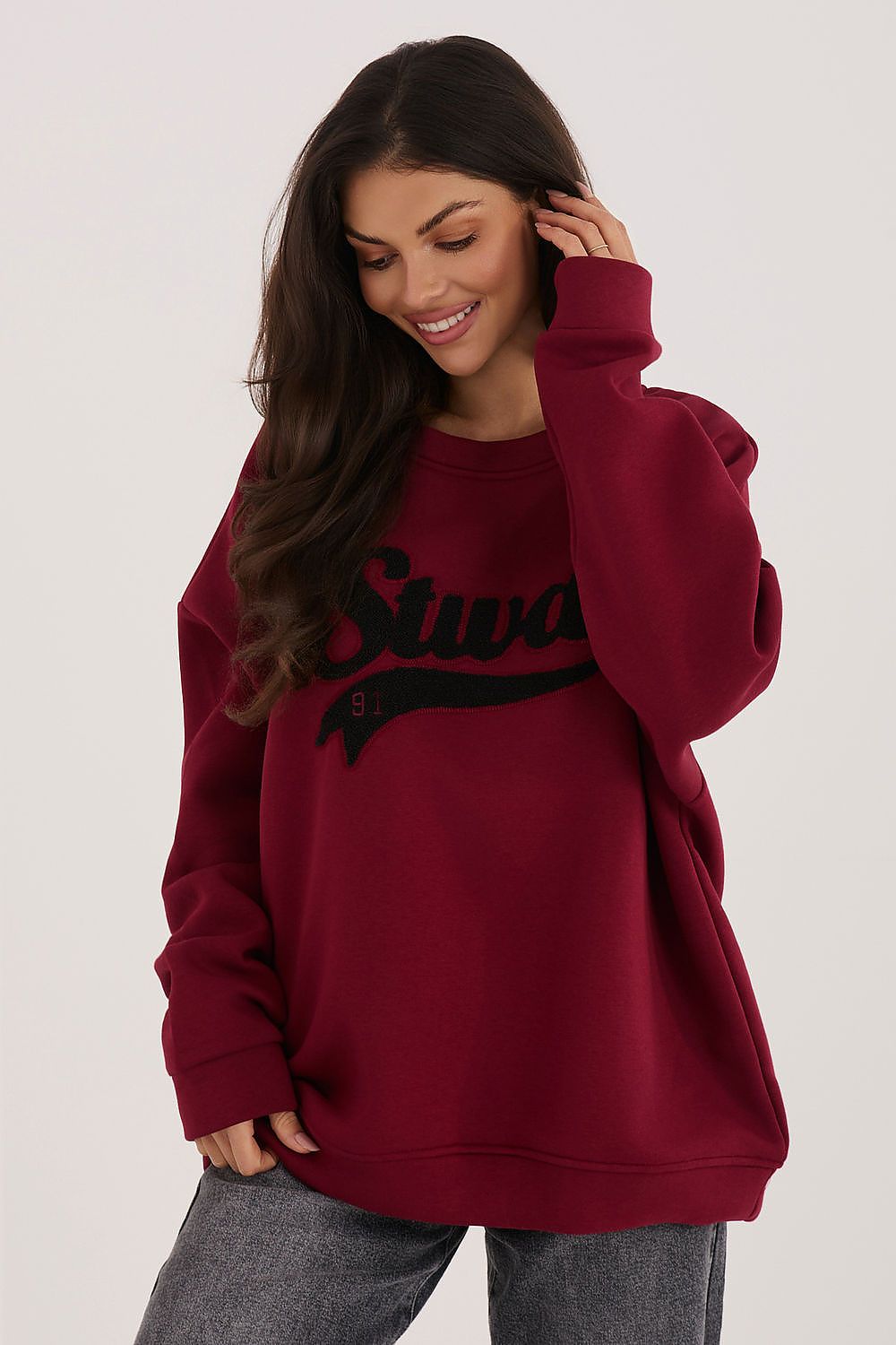 Woman wearing a maroon sweatshirt with text on a plain background