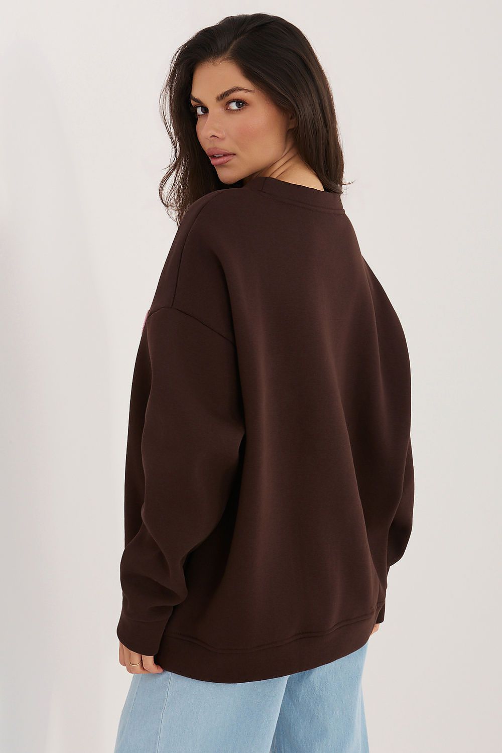 Woman wearing a brown sweatshirt on a plain background