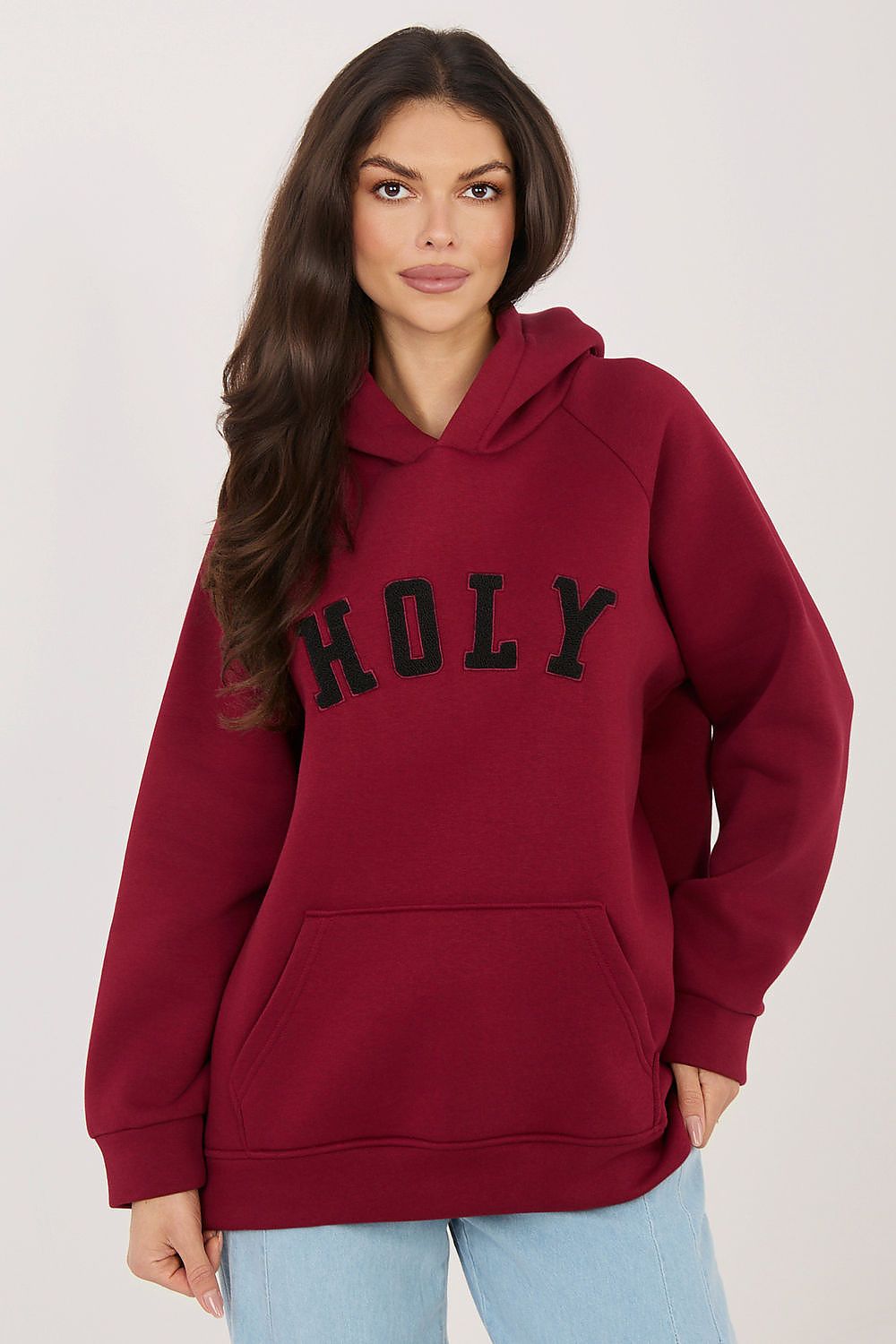 Woman wearing a red hoodie with 'HOLY' text on a plain background