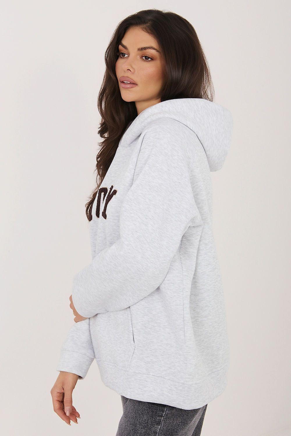 Woman wearing a gray hoodie with text on a plain background