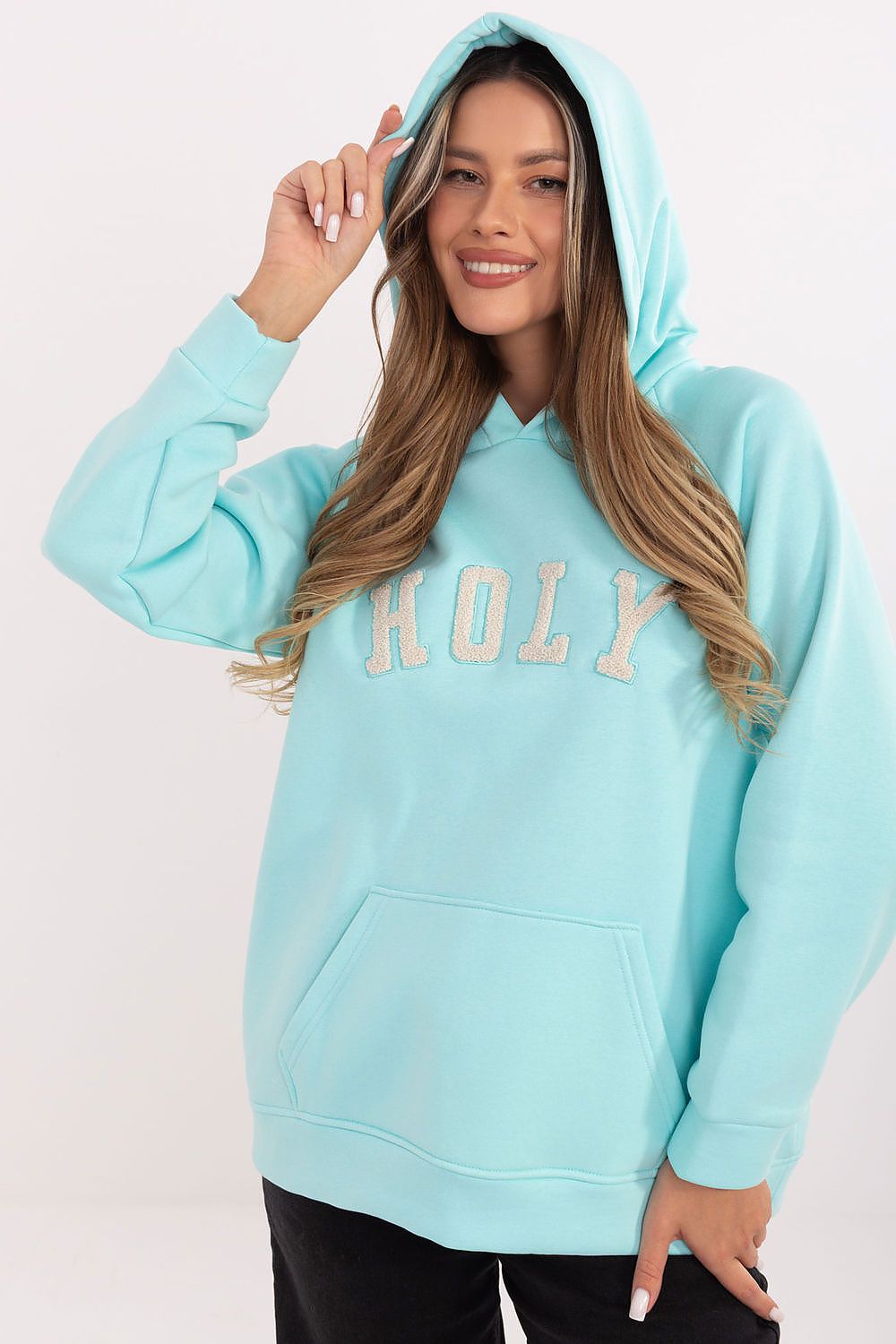 Woman wearing a light blue hoodie with 'HOLY' text on a white background