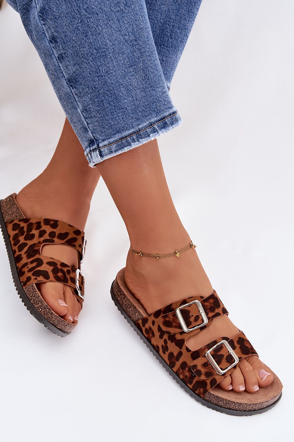 Leopard print sandals worn with rolled-up jeans on a light background