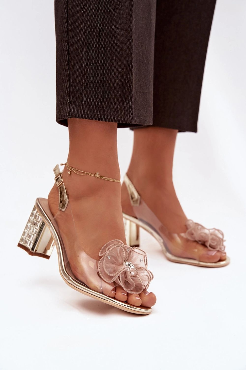 Tan high-heeled sandals with floral designs on a white background