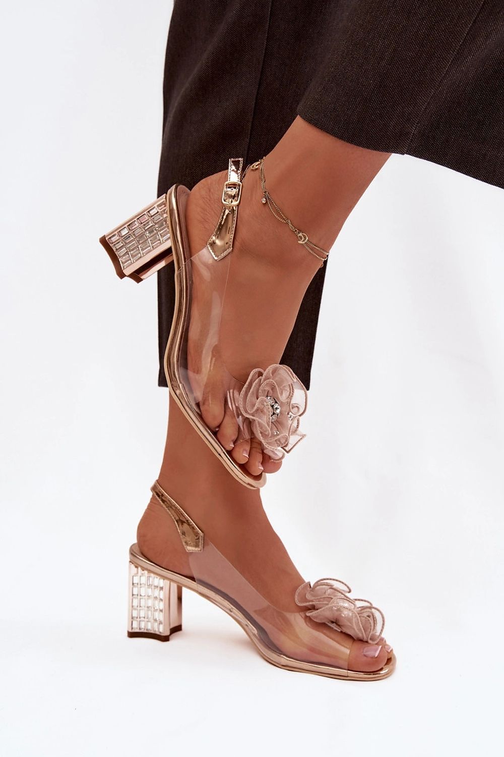 Brown high-heeled shoes with clear straps and decorative elements on a white background