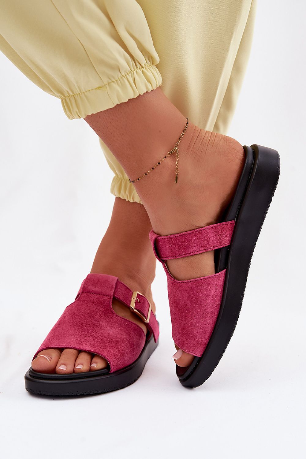 Pink sandals with black soles worn by a person on a white background
