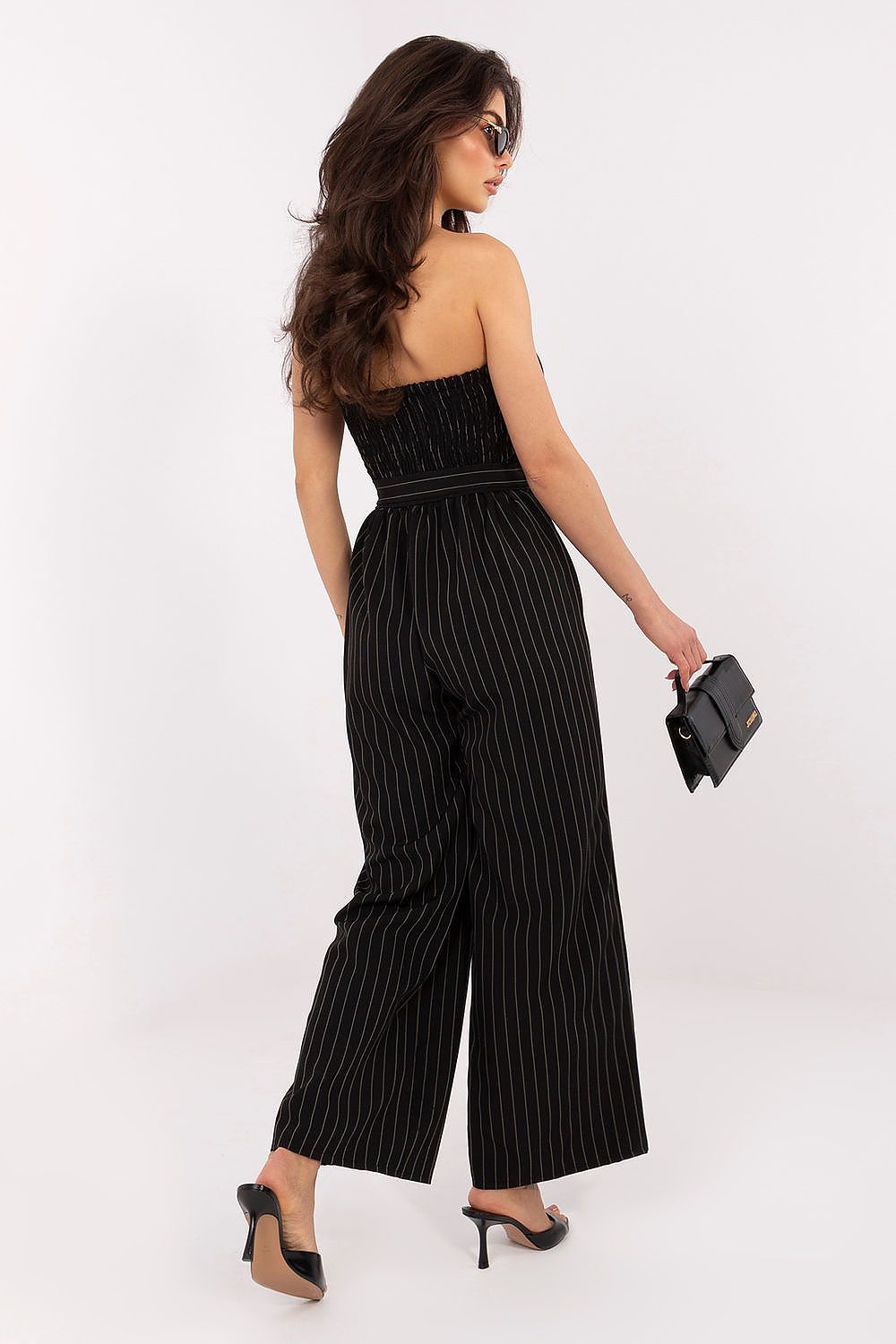 Woman wearing a black pinstripe jumpsuit on a white background