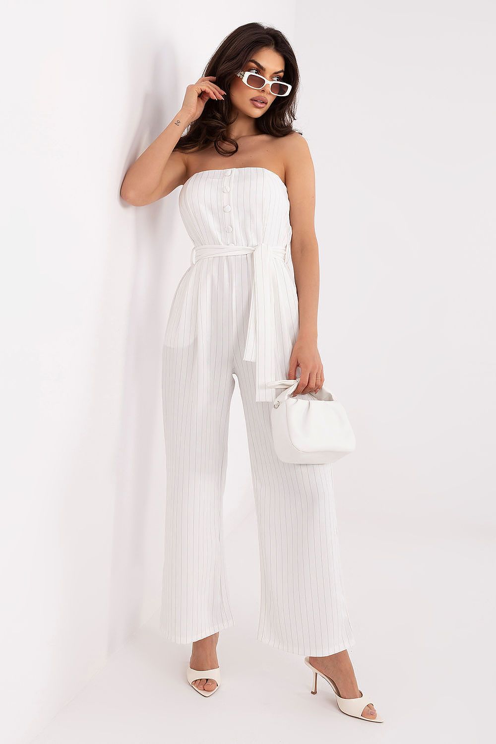 Woman wearing a white strapless jumpsuit against a white background