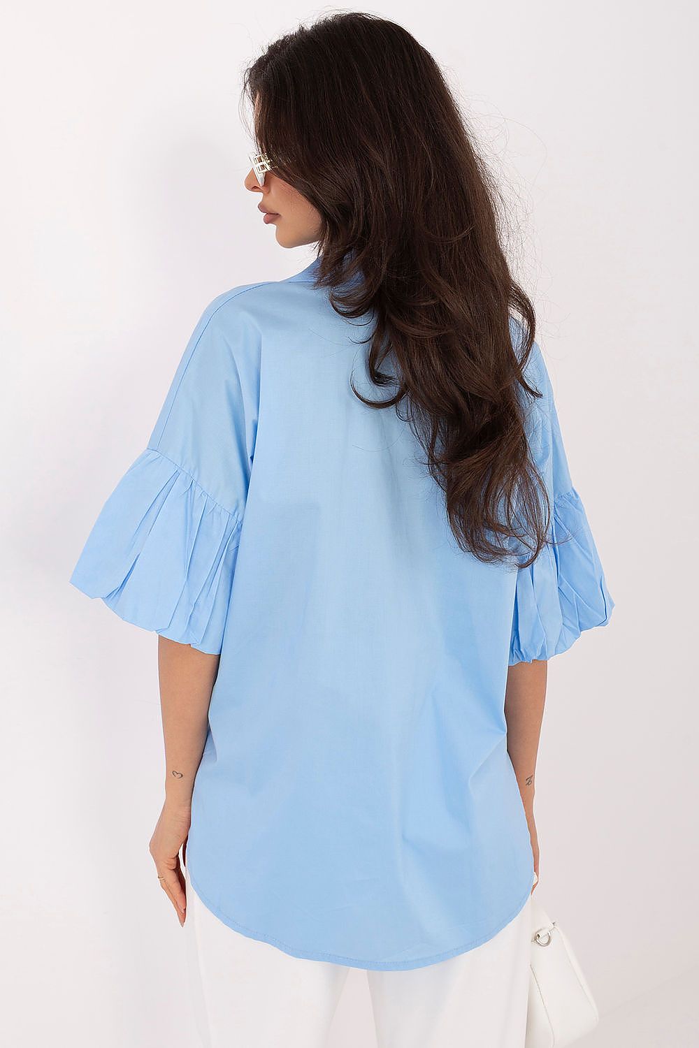Woman wearing a light blue shirt with ruffled sleeves on a white background