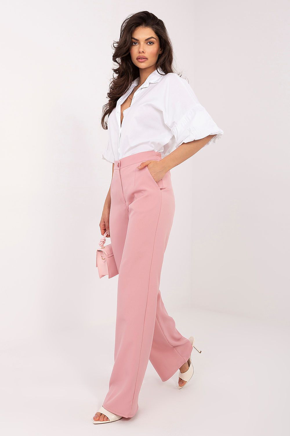 Woman wearing a white shirt and pink pants on a white background