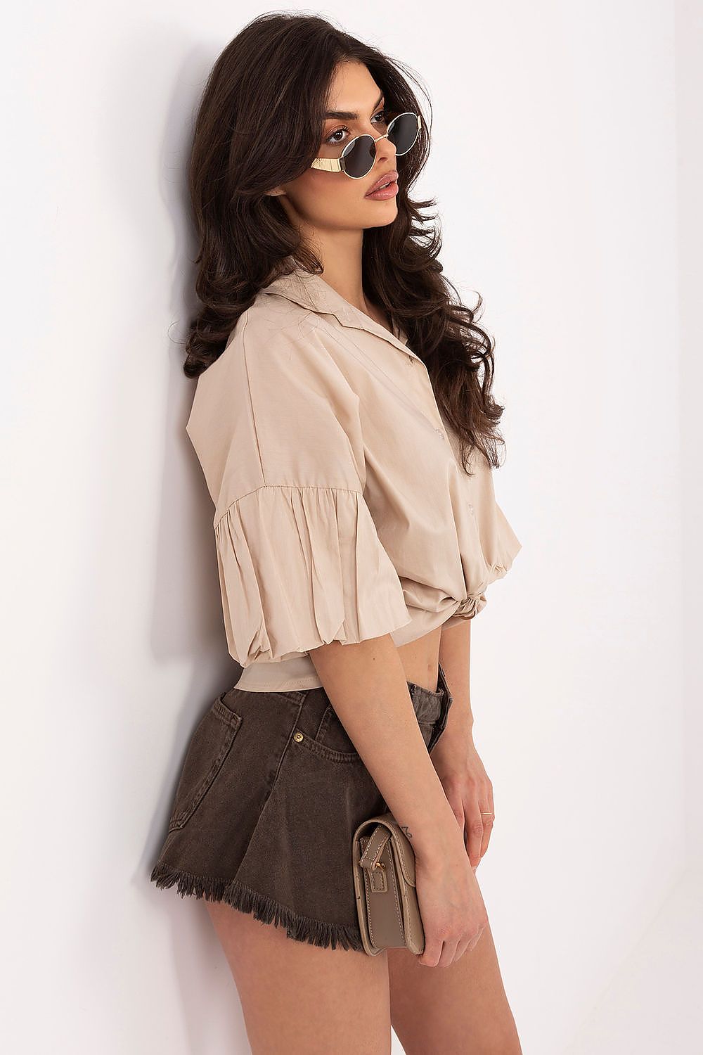 Woman wearing a beige blouse and brown skirt against a white background