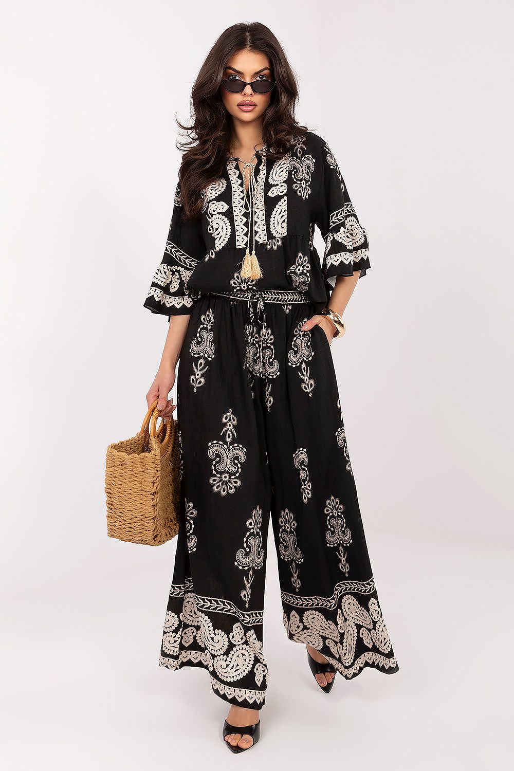 Woman wearing a black and white patterned outfit with wide-leg pants on a white background